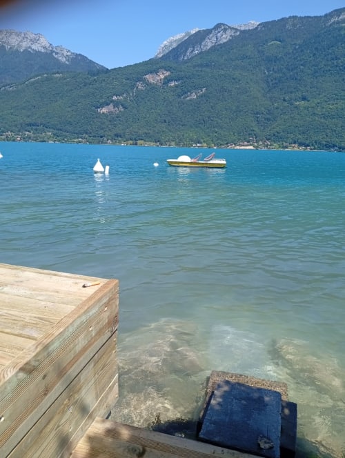 Vue du lac turquoise depuis la terrasse en bois du gîte de Chaparon à Lathuile, avec les montagnes alpines