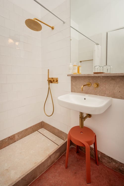 Banheiro moderno com acabamentos em latão, azulejos brancos subway, banqueta coral e detalhes em terracota na pousada Monte das Açoteias