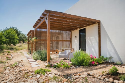 Aconchegante casa branca com pérgola de madeira em Monte das Açoteias, com flores rosa e ambiente de jardim em Tavira, Portugal