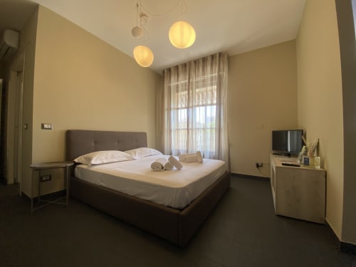 Modern bedroom at Cinelli Apartment in Vercelli with queen bed, pendant lights, TV, and garden view