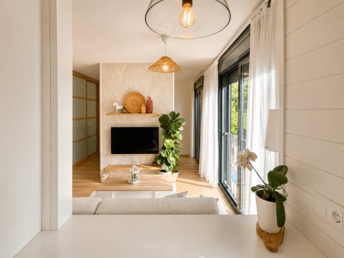 Moderno dormitorio de hotel en Holibai, Baiona, con suelos de madera, TV montada en pared, luces colgantes y puertas correderas de cristal hacia
