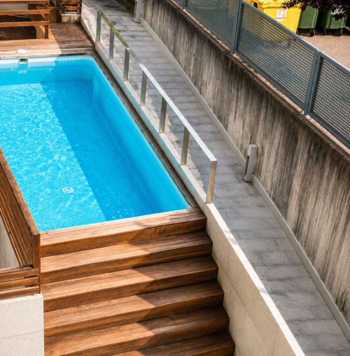 Piscina elevada con deck de madera y barandilla metálica en el hotel Holibai de Baiona, España