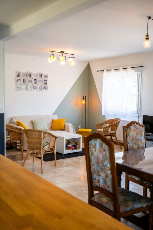 Salon moderne de La Maison Du Saule B&B à Faverolles sur Cher avec fauteuils en osier, art mural géométrique et éclairage chaleureux