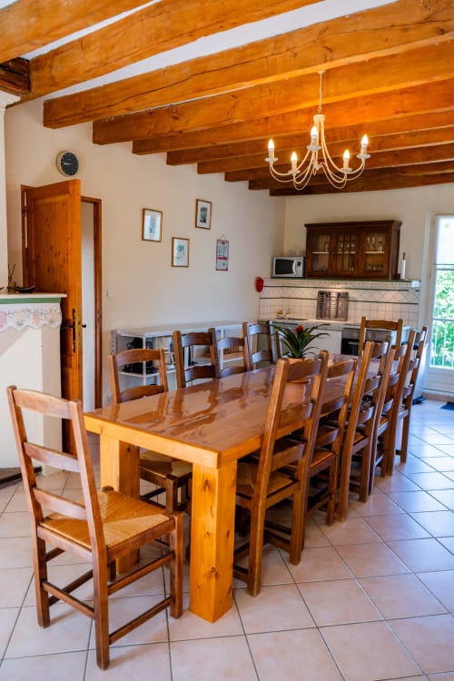 Spacieux séjour de la maison d'hôtes La Maison Du Saule à Faverolles sur Cher, aux poutres apparentes, grande table et chaises rustiques.