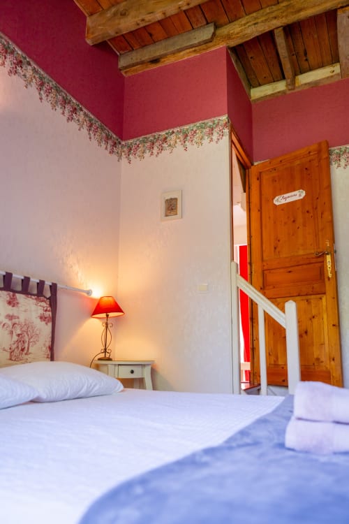 Chambre de charme à la Maison Du Saule avec murs roses, poutres en bois et vue sur le jardin à Faverolles sur Cher
