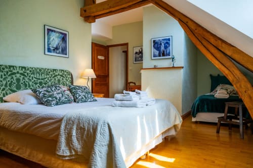 Chambre spacieuse au gîte La Maison du Saule avec tête de lit patterné, poutres et parquet en bois à Faverolles-sur