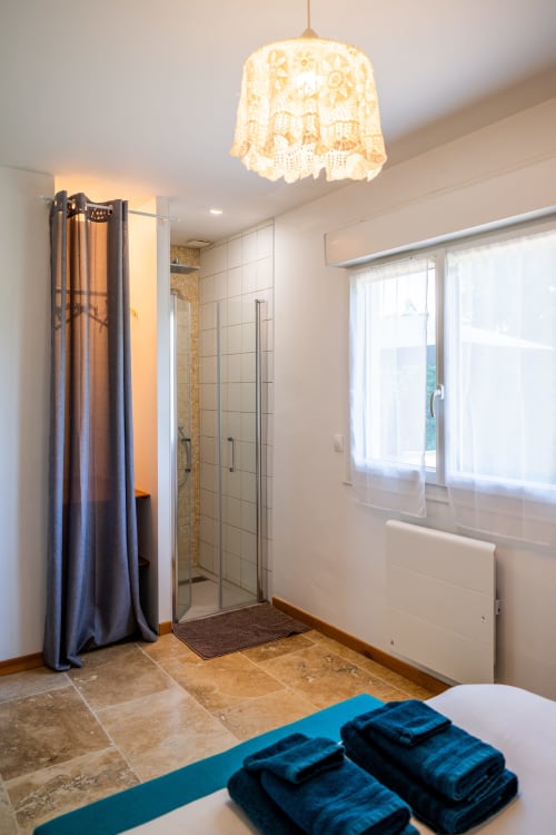 Salle de bain moderne avec douche à l'italienne, serviettes bleues et luminaire suspendu en dentelle à La Maison Du Saule à Faverolles-sur-Cher