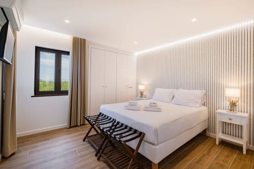 Quarto moderno em Atlantic Places Albufeira com cama de casal, parede com padrão listrado e vista para o jardim