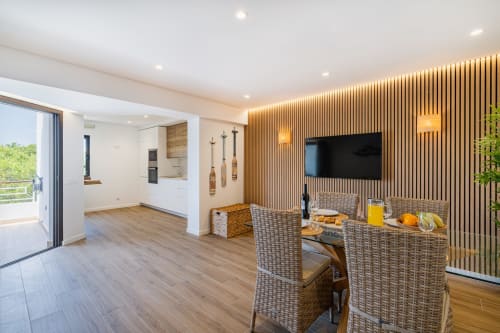 Área de estar de apartamento moderno no Atlantic Places Salgados Hideaway em Albufeira com cadeiras de trançado e parede de destaque em madeira
