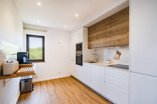 Cozinha moderna no apartamento Salgados Hideaway em Atlantic Places, Albufeira, com armários brancos, bancadas de madeira e