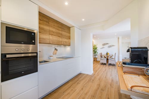 Cozinha moderna com armários brancos, acabamentos em madeira e eletrodomésticos no apartamento Atlantic Places Salgados Hideaway