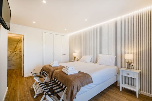 Quarto moderno na Atlantic Places Albufeira com camas gêmeas, guarda-roupa branco, parede com listras e piso em madeira