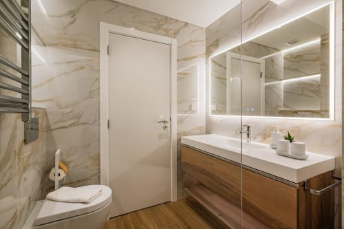 Banheiro moderno do apartamento Atlantic Places Salgados Hideaway em Albufeira com paredes de mármore, bancada de madeira e espelho LED