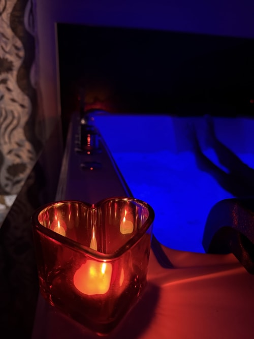 Candela rossa a forma di cuore che brilla nella camera Zappy Domus con illuminazione blu e vista sulla città