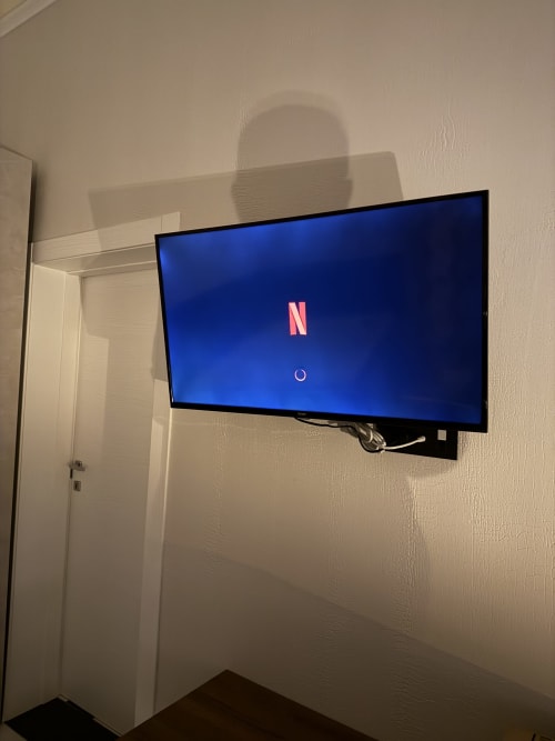Netflix in caricamento sulla TV a schermo piatto nella camera con letto queen del Zappy Domus, con pareti color crema e porta bianca