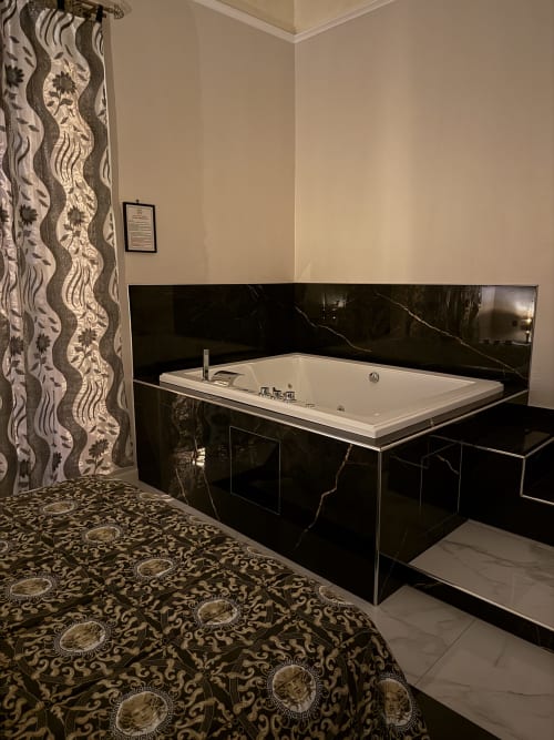 Lussuosa vasca idromassaggio con cornice in marmo nero nella suite Zappy Domus, Italia