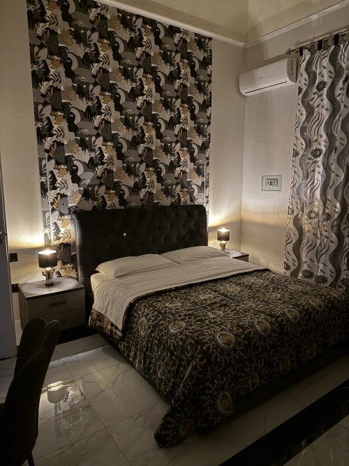 Camera elegante a Zappy Domus con letto imbottito nero, carta da parati decorativa, aria condizionata e illuminazione moderna