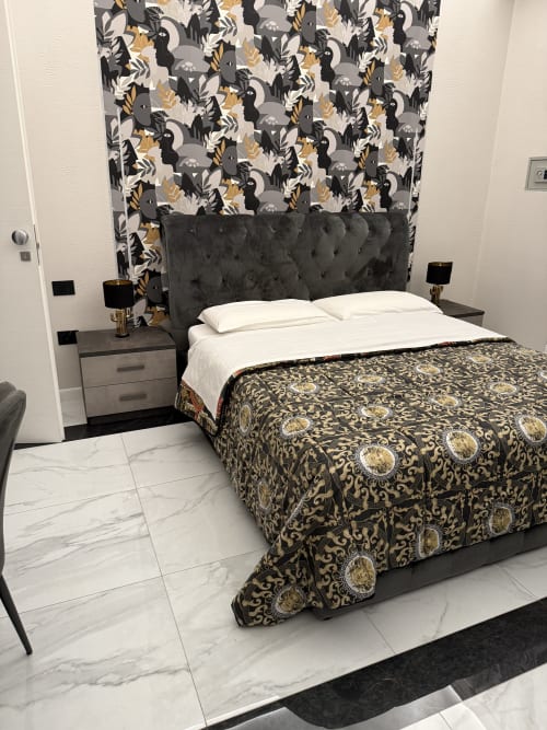 Camera da letto moderna a Zappy Domus con testata trapuntata grigia, carta da parati decorativa, biancheria bianca e pavimenti in marmo.