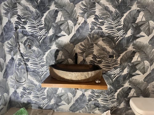 Lavabo moderno in pietra con carta da parati a foglie tropicali nella camera Zen di Zappy Domus, Italia