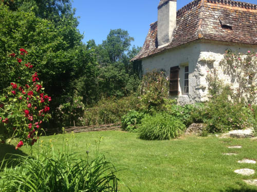 Vue du jardin de la chambre d'hôtes Les 2 Brigards à Monestier, France avec roses rouges, cottage blanc et pelouse verdoyante