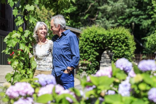 Couple savourant un moment paisible au jardin de la maison oubliée, charmant gîte à Goetzenbruck, entouré de fleurs