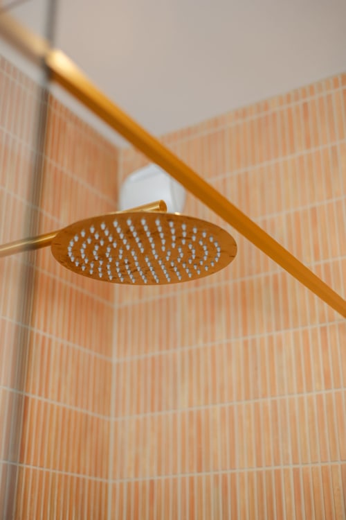 Pomme de douche dorée dans la salle de bain moderne de L'Ode à Pierre B&B, Dax, aux murs carrelés de terre cuite