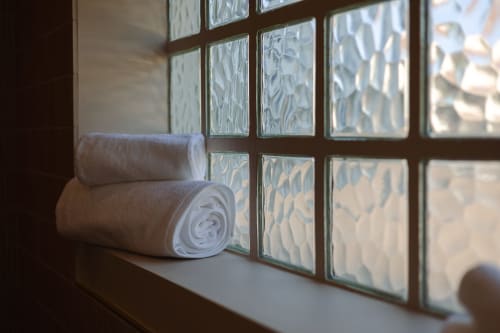 Serviettes blanches roulées sur l'appui de fenêtre de la maison d'hôtes L'Ode à Pierre à Dax, avec vitraux décorés