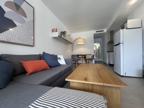 Moderno apartamento estudio en FTV Holidays Homes, La Oliva, con sofá gris, mesa de madera y cocina americana