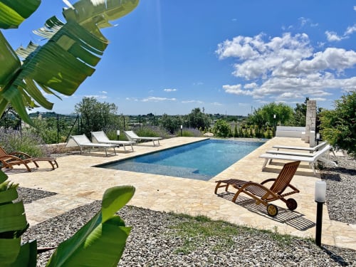 Terrazza piscina di lusso alla villa Pietra & Luce a Ostuni con lettini, piscina rettangolare blu e vista sulla campagna