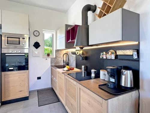 Cucina moderna con mobili in legno, piani di lavoro neri e elettrodomestici in acciaio inossidabile nella villa di Ostuni