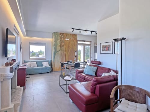 Zona living moderna della villa Pietra & Luce a Ostuni con divano bordeaux, spazio pranzo e ampie finestre luminose
