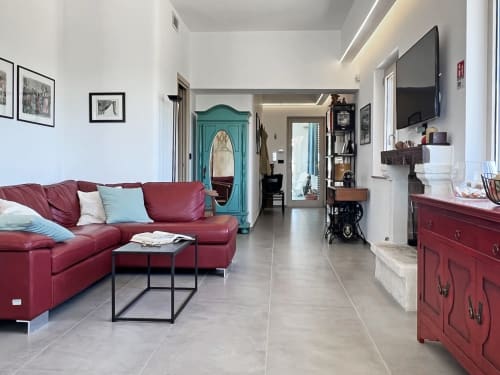 Zona living della villa Ostuni Bloom con divano bordeaux, mobile turchese e comfort moderni presso Pietra & Luce