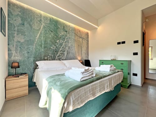 Camera da letto moderna della villa Pietra & Luce a Ostuni con parete accento verde, biancheria bianca e arredamenti contemporanei