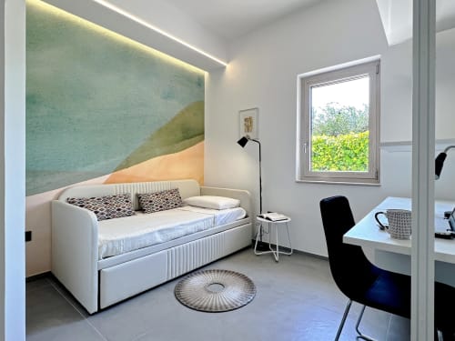 Camera moderna nella villa Pietra & Luce a Ostuni con letto diurno, arte murale geometrica, scrivania e vista sul giardino