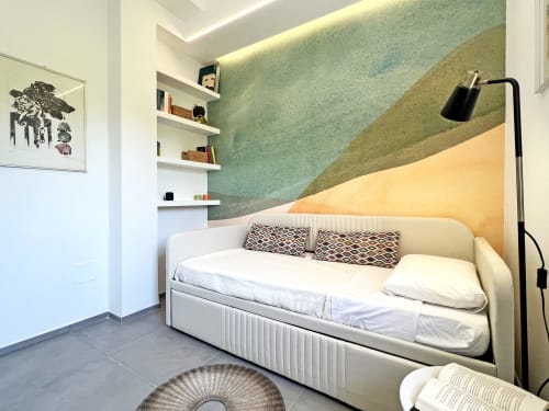 Camera moderna nella villa Pietra & Luce a Ostuni con letto giorno color crema, parete accent verde, ripiani integrati e lampada da terra nera