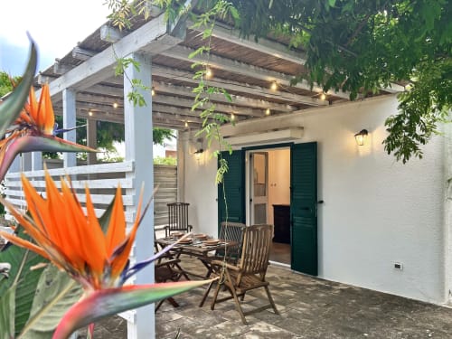 Affascinante patio di villa a Pietra & Luce a Ostuni con pergolato, fiori tropicali, zona pranzo e porte con imposte verdi