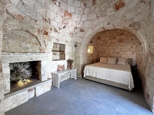 Camera in pietra nella villa di Ostuni con camino, letto e soffitto a volta presso Pietra & Luce