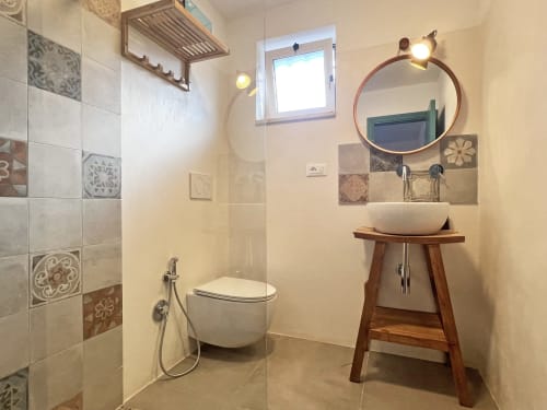 Bagno moderno della villa Pietra & Luce a Ostuni con lavabo a catino, specchio rotondo e accenti di piastrelle decorative