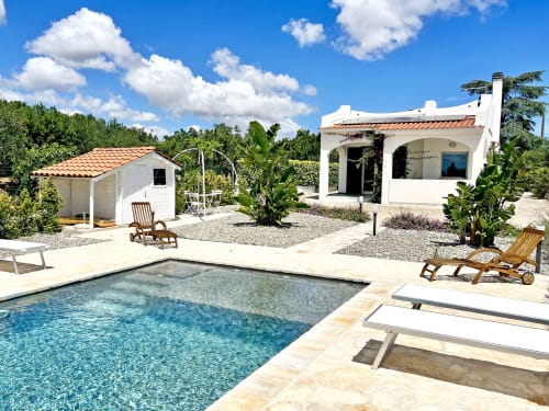 Villa Ostuni Bloom con vista sulla piscina, architettura mediterranea bianca, lettini e rigogliosi giardini sotto cielo azzurro