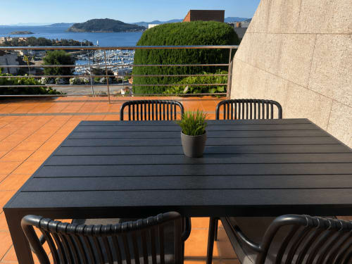 Mesa de comedor negra con sillas en la terraza Holibai con vistas a la marina y bahía de Baiona