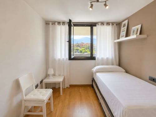 Dormitorio luminoso en Holibai, Baiona, con cama, vistas al casco histórico, suelo de madera y mobiliario moderno