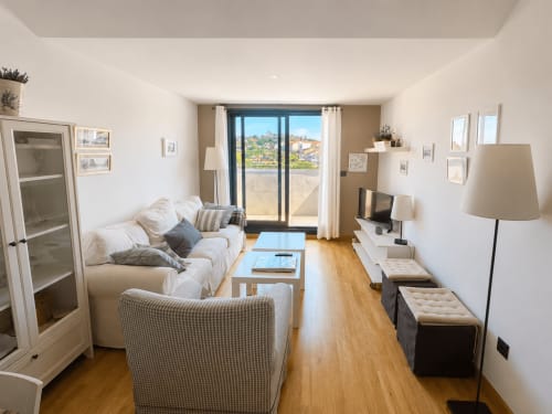 Moderna sala de estar del hotel Holibai en Baiona con asientos confortables, pisos de madera y vistas al mar