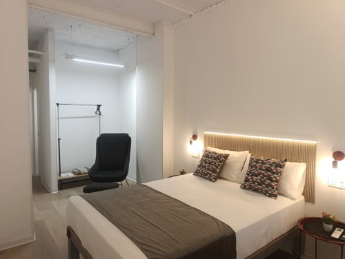 Habitación moderna en El Rincón de Sevilla con cama queen, rincón de lectura con silla negra e iluminación ambiente en San Juan de