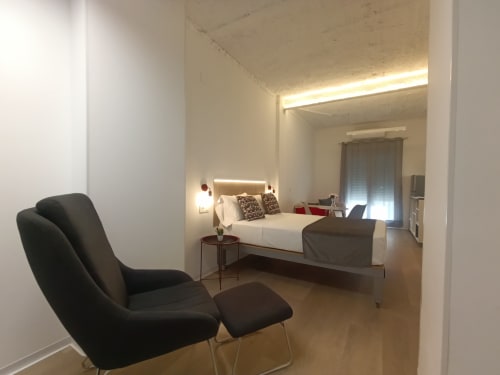 Dormitorio moderno en El Rincón de Sevilla con cama doble, sillón negro y iluminación ambiental contemporánea