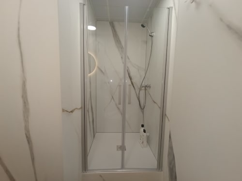 Moderno baño con ducha de cristal y revestimiento con efecto mármol en el apartamento El Rincón de Sevilla, San Juan de Aznalfarache