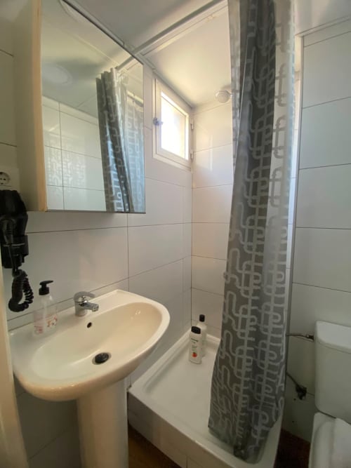 Baño limpio en apartamento El Rincón de Sevilla con lavamanos blanco, bañera, cortina de ducha y espejo en el distrito de Macarena