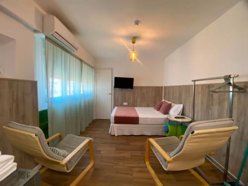 Dormitorio moderno en apartamento El Rincón de Sevilla con cama, TV, sillas de madera y vistas a la ciudad cerca del barrio de Macarena