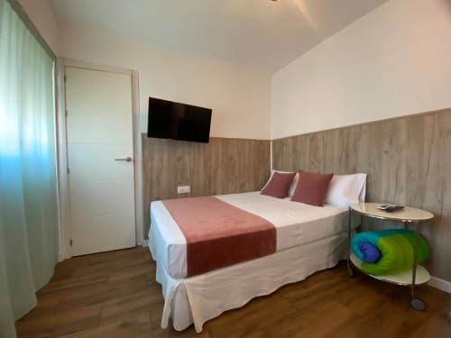 Moderno dormitorio en apartamento El Rincón de Sevilla con cama queen, TV de pared, cabecero de madera y diseño contemporáneo