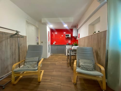 Sala moderna en El Rincón de Sevilla con sillas de madera, cocina roja y comodidades en Sevilla