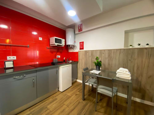 Cocina moderna con azulejos rojos, muebles grises y mesa de comedor en El Rincón, Sevilla